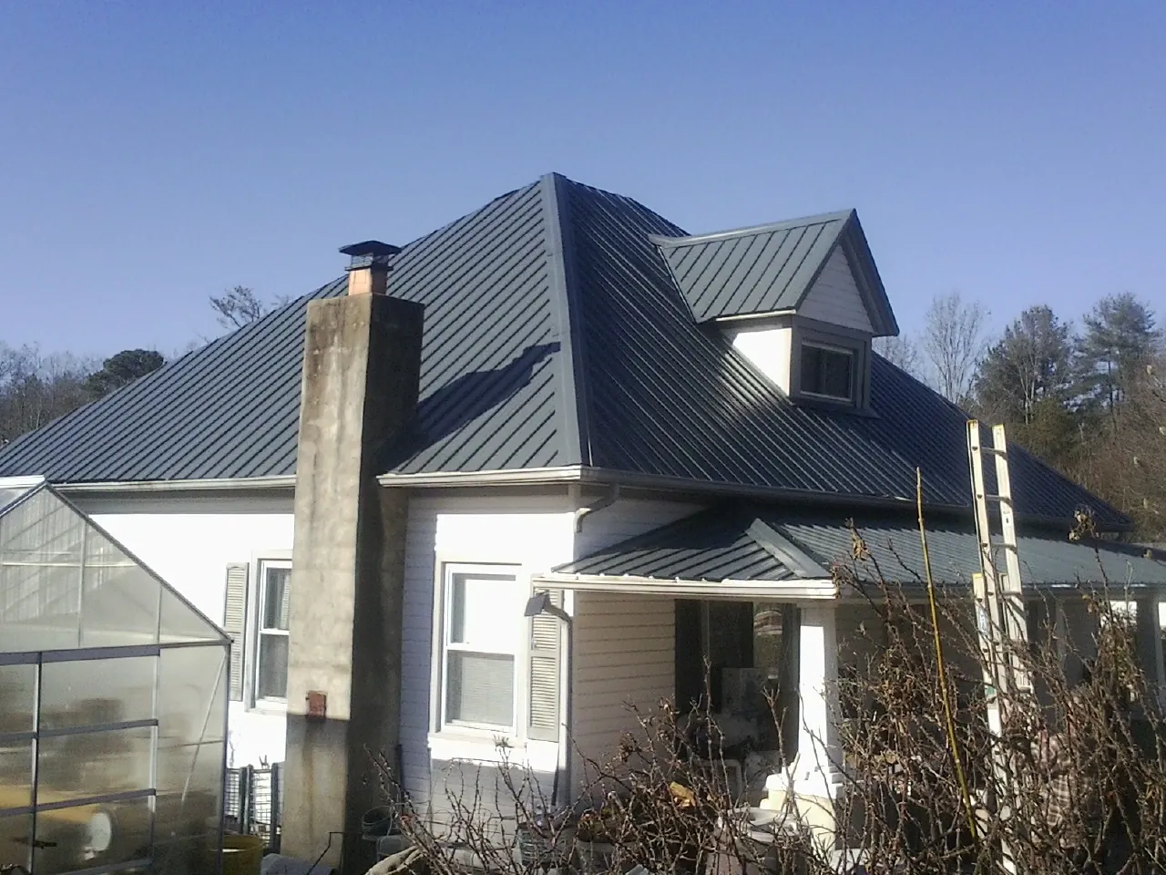 Dark blue standing seam metal roof on a white farmhouse with dormer — Slate & Tile Roof Repair by Roofing Brothers in Warrior
