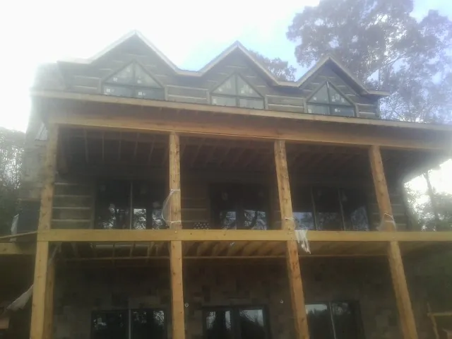 Dormers and porch framing on a large log home under construction — Roof Coating work by our crew in Warrior