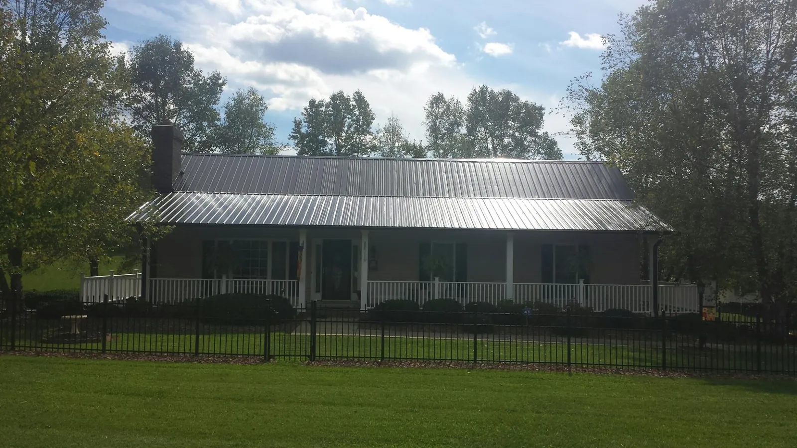 Gray metal roof on a brick ranch with a full width front porch — Gutter Guard Installation work by our crew in Warrior